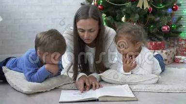 另一位年轻的母亲带着两个孩子在圣诞树附近的地板上看书